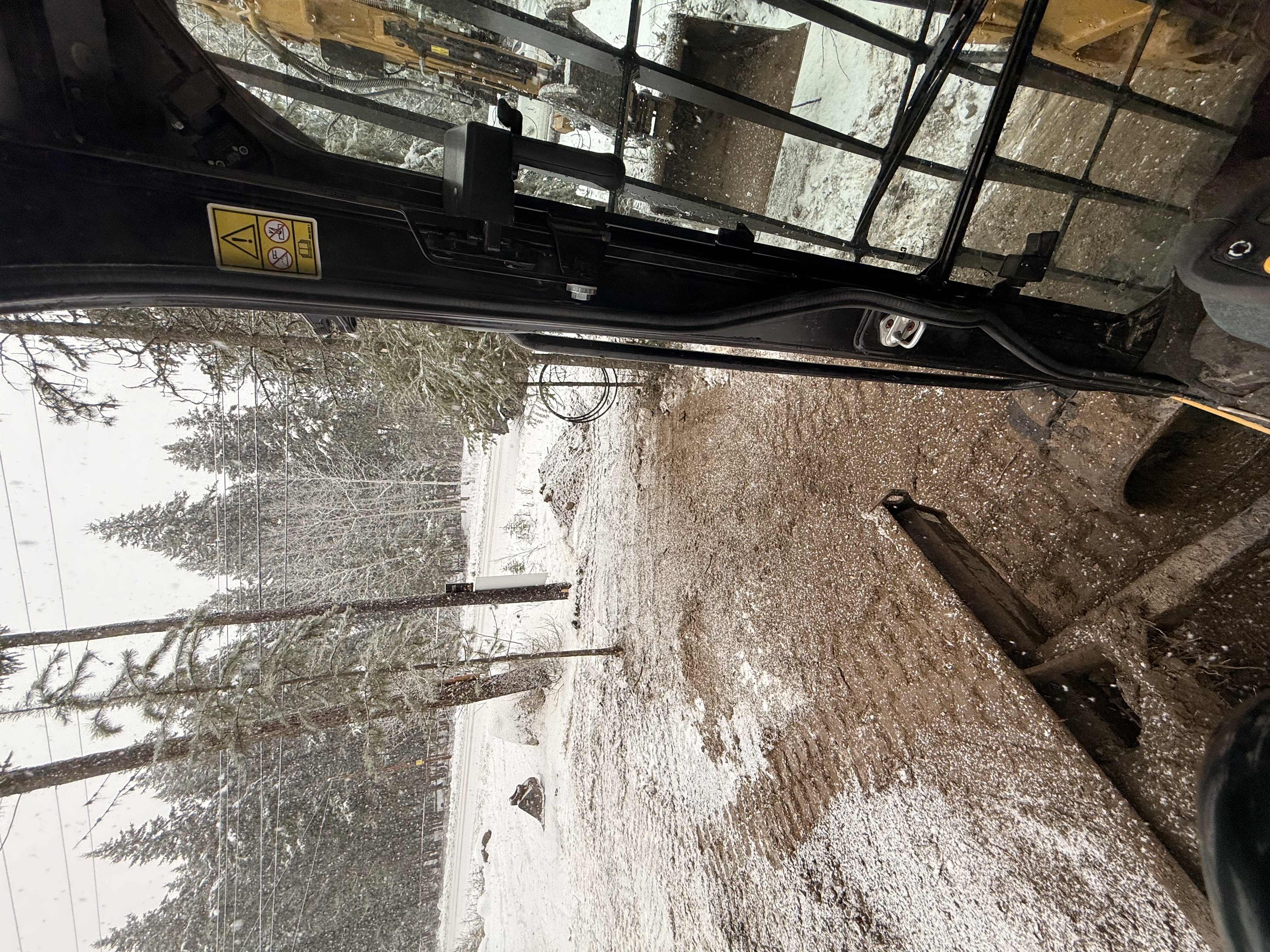 View from CAT 305 cab while trenching in winter near 100 Mile House