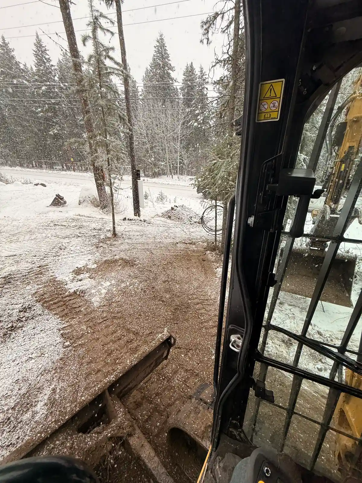 View from CAT 305 cab while trenching in winter near 100 Mile House